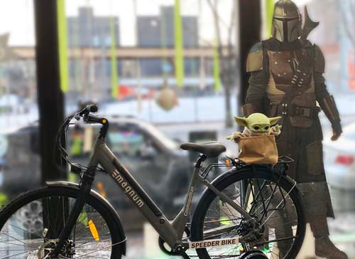 Star Wars Mandalorian figure standing besides an Magnum Cosmopolitan ebike bike with the child character on the rear rack
