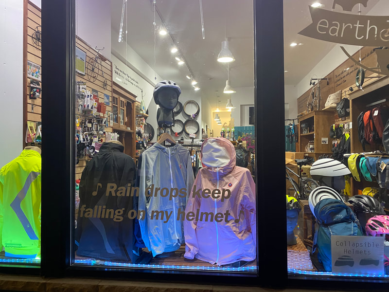 Waterproof raincoats and bike helmets in Earth Rider bike  shop window 