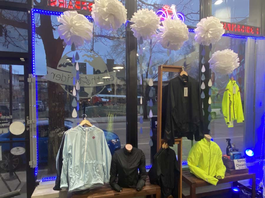 Window display with paper clouds and rain drops over rain coats