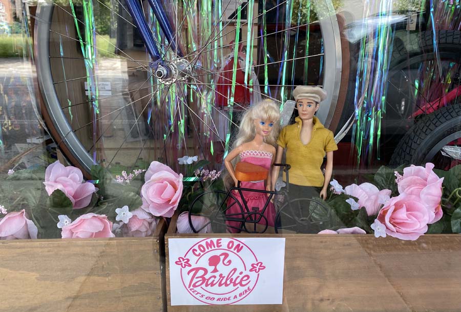 Earth Rider shop window with Barbie and Ken dolls and a bike with slogan, let's ride a bike