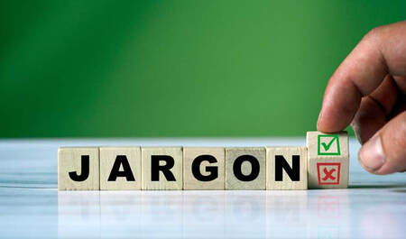 Block letters spelling out the word JARGON with a person's hand arranging the blocks