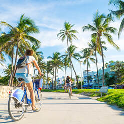 Riding a bike in Miami Beach with sun and palm trees