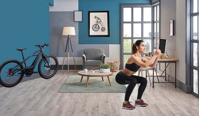 Woman doing squats at home with her bike in the room