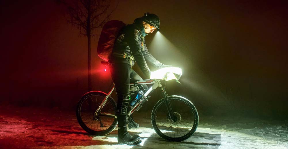Cyclists at night stopped to look at a map with front and rear lights
