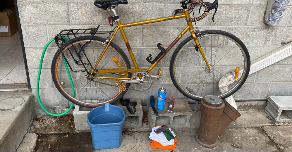 Bike and equipment ready to be cleaned, hose, bucket, rags, brushes, and cleaners