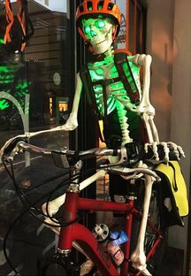 A lit up skeleton sitting on a bike