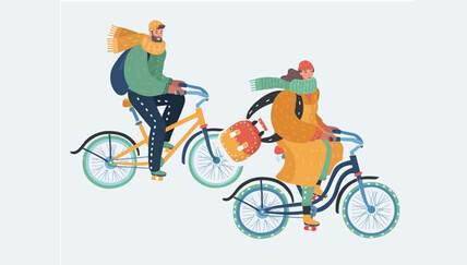 Two riders bundled up riding bikes in the winter