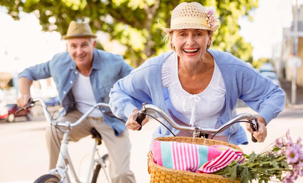 Baby boomer man and woman adjults riding comfort bikes and smiling