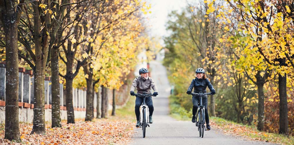 Senior man and woman riding bikes ourdoors in the fall