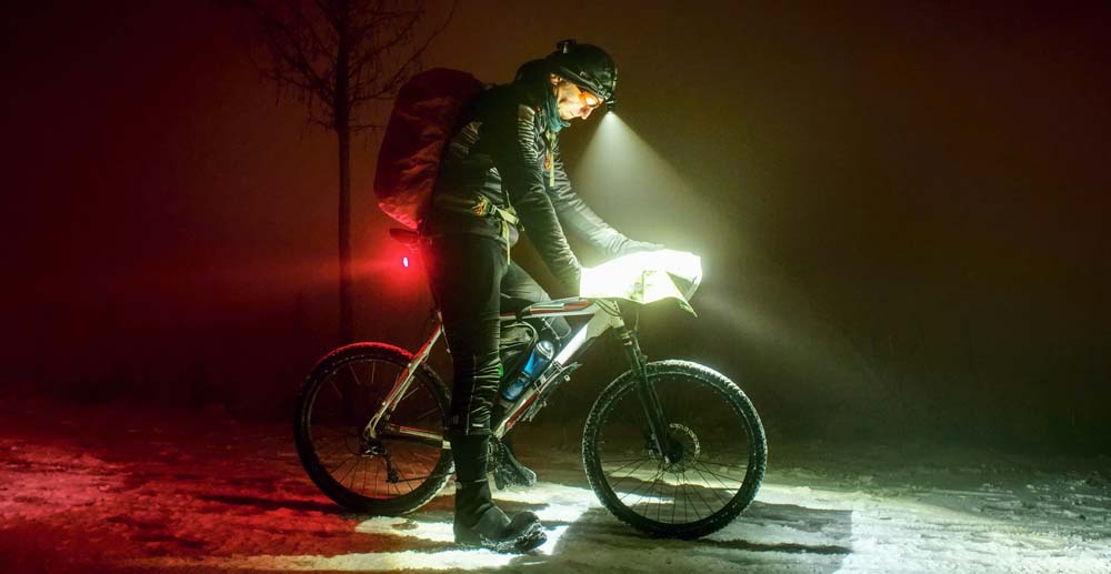 Person at night on a bike dressed warmly and sporting bike lights